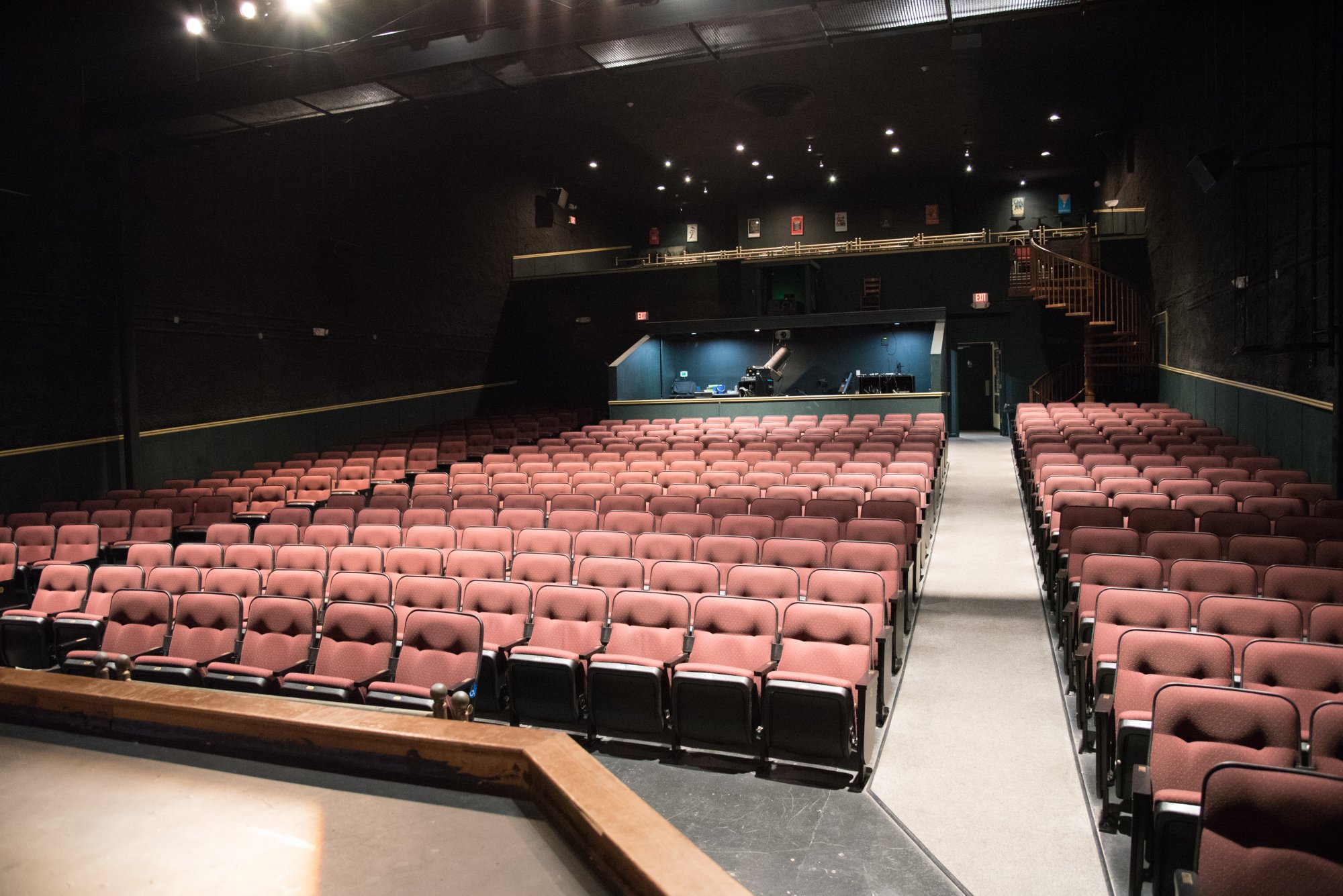 Rows of empty red seats in an Elbert Theatre rental space facing a stage, with a balcony level at the back.