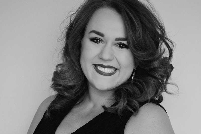 A smiling woman with shoulder-length wavy hair at the Elbert Theatre Foundation.